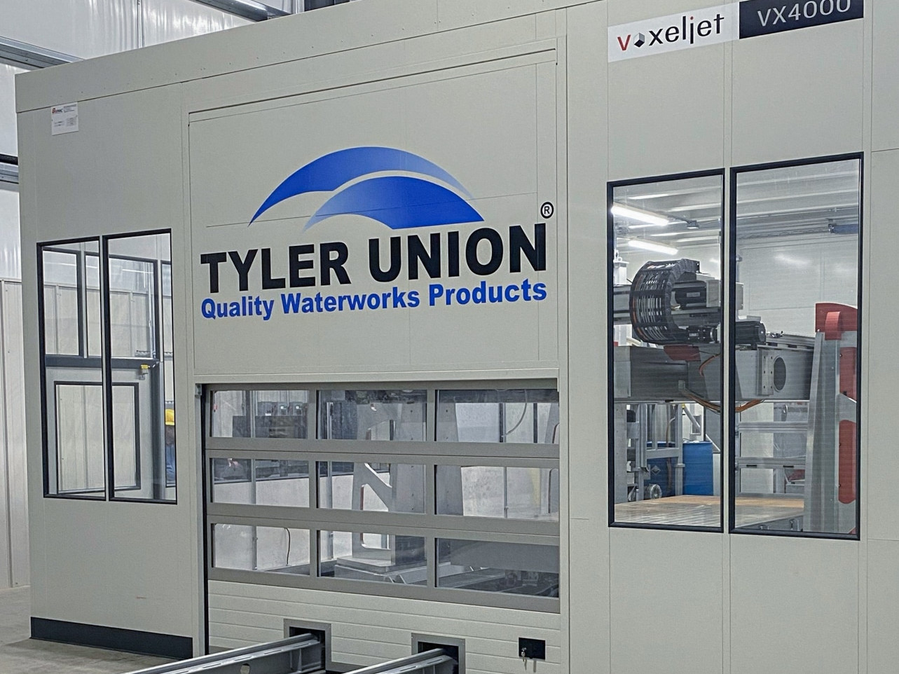 A picture of the VX4000 3D sand printer from voxeljet, installed and showing the logo of Tyler Union Quality Waterworks Products.